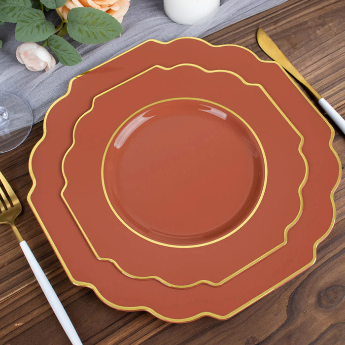 Elegant terracotta plates with gold trim stacked on a wooden table.