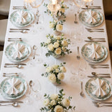 Elegant wedding reception table setting with white roses, green accents, and crystal glassware