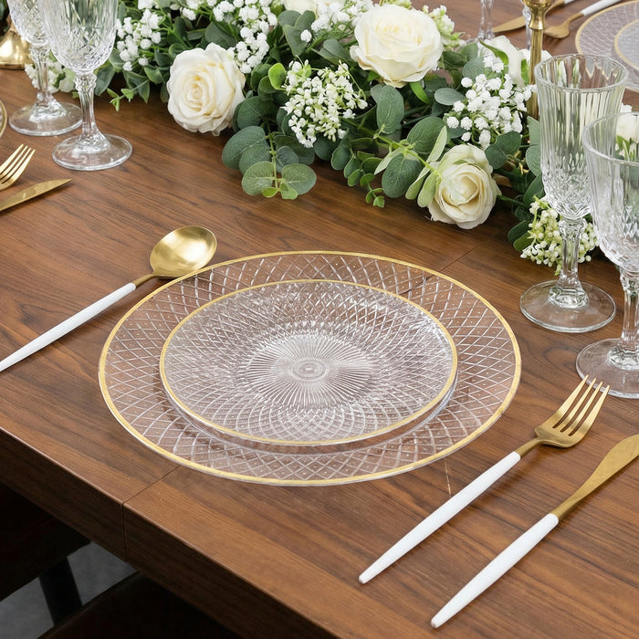 Elegant clear glass plates with gold trim on a wooden dining table setting.