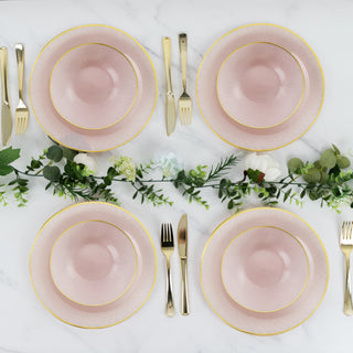 Elegant pink plates with gold trim arranged on a marble table with greenery accents.
