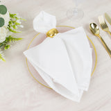 Elegant white napkin with gold ring on a pink plate, set for dining.