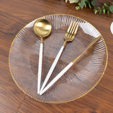 Elegant clear plate with gold trim and gold-accented cutlery set.