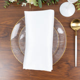 White napkin on a clear plate set on a wooden table.