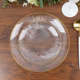 Clear glass plate with ribbed design and gold trim on wooden table.