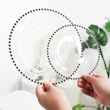 Clear plates with black beaded rim, held in hands against a plain backdrop.