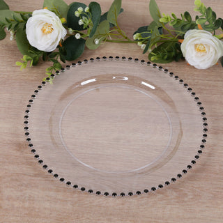 Clear decorative plate with black beaded rim on wooden surface.
