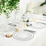 Elegant dining table set with clear plates and floral decor.