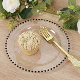 Clear decorative plate with a cupcake and gold fork on a wooden table.