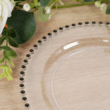Clear glass plate with black beaded edge, surrounded by greenery and floral accents.