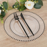 Elegant clear plate with black cutlery and decorative edge on wooden table.