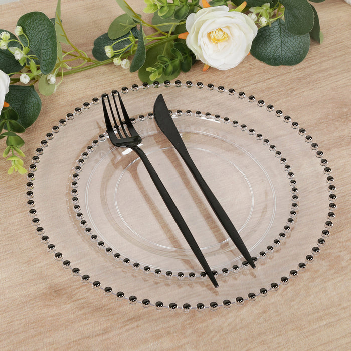 Elegant clear plate with black cutlery and decorative edge on wooden table.