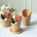 Cardboard cups filled with cheese, meats, fruits, and crackers on a white surface.