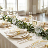 Elegant wedding reception table with gold accents, greenery, and champagne glasses
