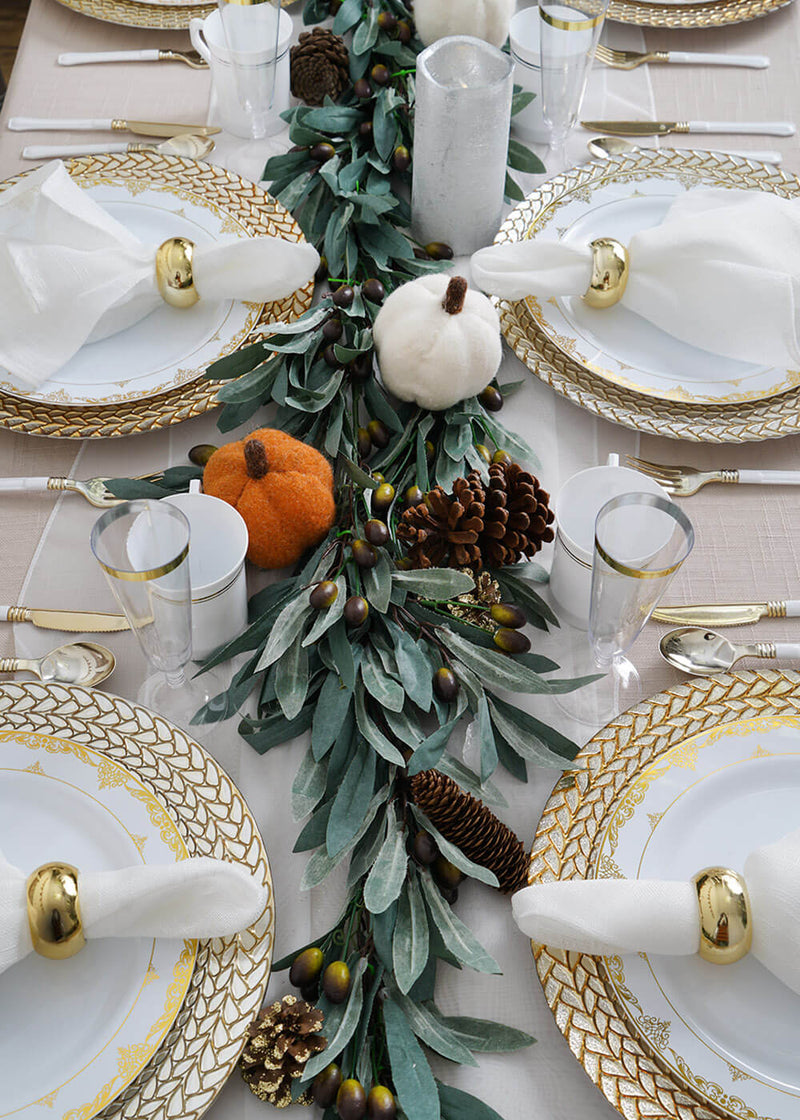 Fall tablescape with gold-rimmed plates and greenery centerpiece