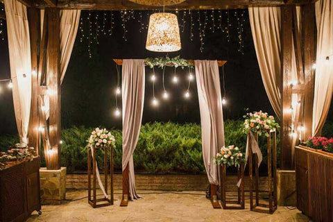 Outdoor wedding arch with drapes and string lights