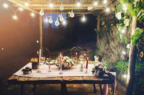 Outdoor dinner table with string lights and flowers