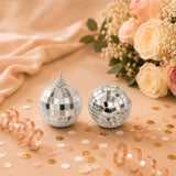 Silver disco ball ornaments with roses and confetti on a peach background