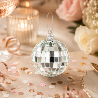 Silver mirrored disco ball ornament on a pastel party table with confetti