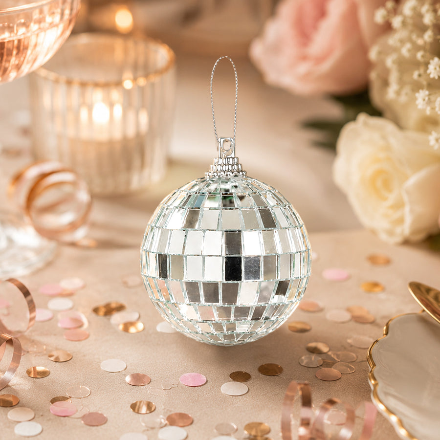 Silver mirrored disco ball ornament on a pastel party table with confetti