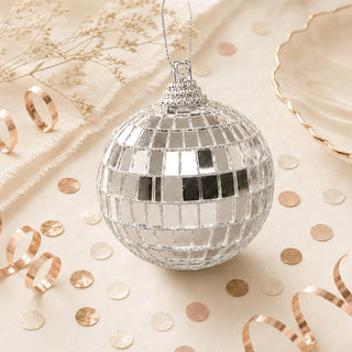 Mirrored disco ball ornament with rose gold confetti on beige background