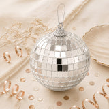 Silver disco ball Christmas ornament with mirrored tiles on a beige background