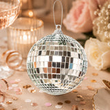 Silver disco ball ornament with rose gold confetti and floral background