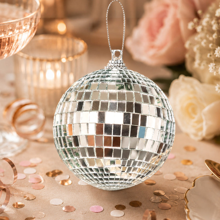 Silver disco ball ornament with rose gold confetti and floral background