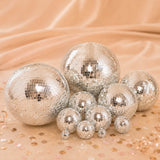 Silver disco balls on a peach background with scattered confetti