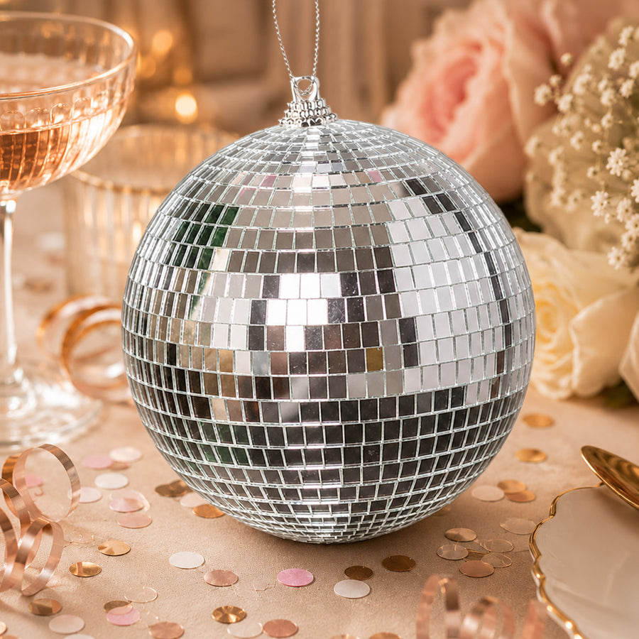 Silver disco ball ornament on a festive party table with confetti and glasses