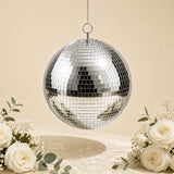 Silver disco ball hanging with white roses and floral decor on beige background