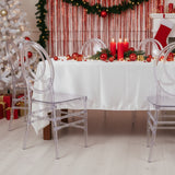 Festive dining table with clear chairs, candles, and holiday decor in a cozy setting.
