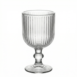 Clear ribbed glass goblet with a round base and decorative stem. #whtbkgd