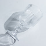Clear ribbed glass with a stem on a plain background.