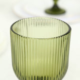 Olive green ribbed glass tumbler on white background