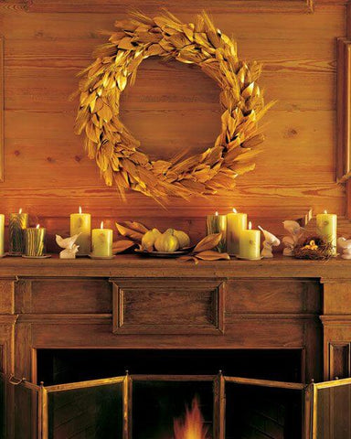 Gold leaf wreath above candles on a mantel