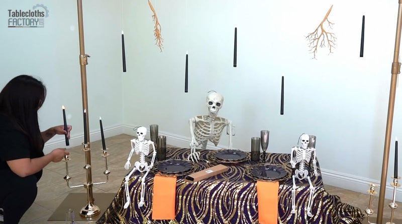 Setting black candles in a gold candelabra to complete a chic Halloween table setup.