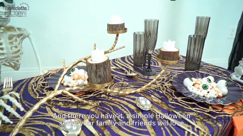 Close-up of a gold branch candle holder and black goblets in a stylish Halloween table setup.