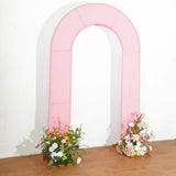 Pink arch backdrop with floral arrangements on either side.