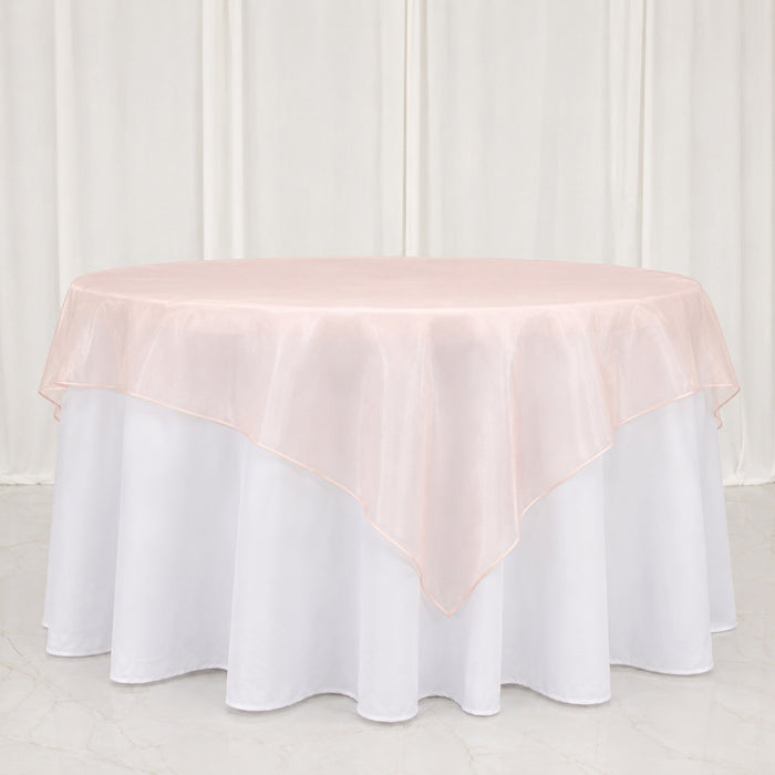 Round table with blush pink overlay and white floor-length tablecloth