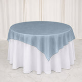 Light blue sheer round table overlay on white tablecloth with draped backdrop