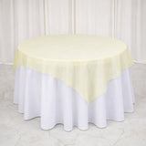 Round table covered with a yellow tablecloth and white skirt.