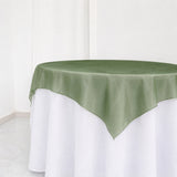 Round table with sage green overlay and white tablecloth in minimalist room