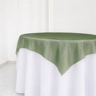 Round table with sage green overlay and white tablecloth in minimalist room