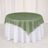 Round table with green sheer overlay and white tablecloth backdrop