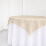 Beige tablecloth draped over a round table in a studio setting.