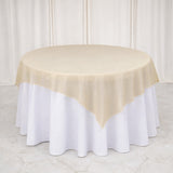Round table with cream overlay on white tablecloth.