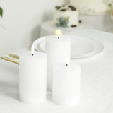 Three white ribbed pillar candles on a table setting.