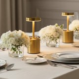 Elegant table setting with gold lamps and white floral arrangements.