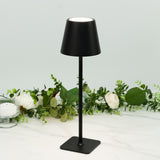 Black table lamp on a marble surface with greenery and candles in the background.