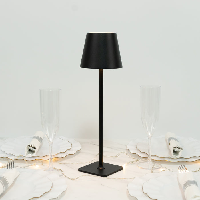 Black table lamp on a dining table with elegant dishware and glasses.
